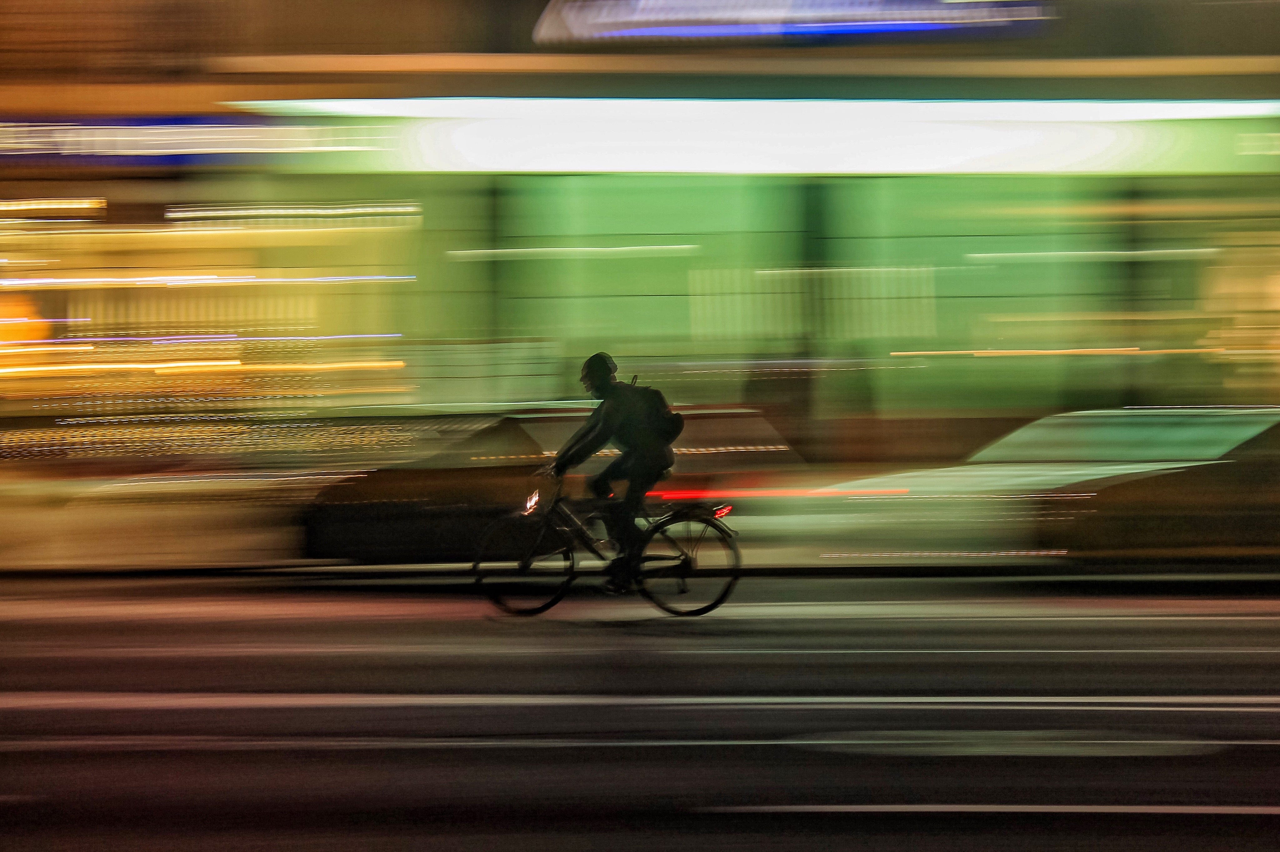 Long-exposure photo of a cyclist moving quickly through city lights